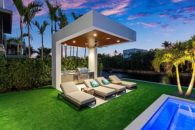 view of patio / terrace featuring an outdoor kitchen, a ceiling fan, an outdoor hangout area, a water view, and a sink