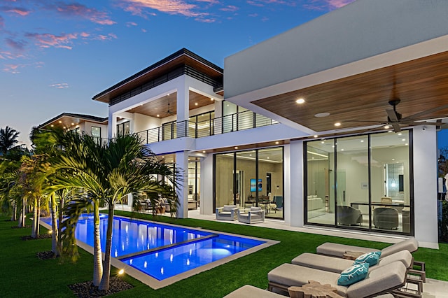 rear view of property with a patio, outdoor lounge area, a lawn, ceiling fan, and a balcony