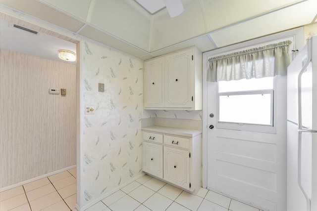 kitchen featuring light tile patterned floors, light countertops, visible vents, freestanding refrigerator, and wallpapered walls