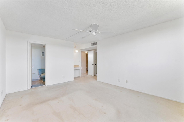 unfurnished bedroom with light colored carpet, visible vents, connected bathroom, a textured ceiling, and ceiling fan