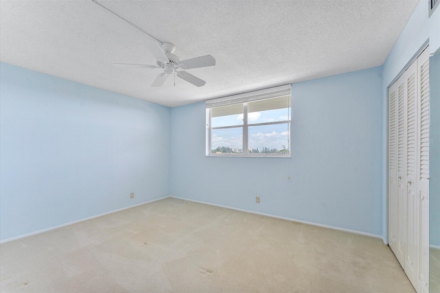 unfurnished bedroom featuring a closet, light colored carpet, a textured ceiling, and baseboards