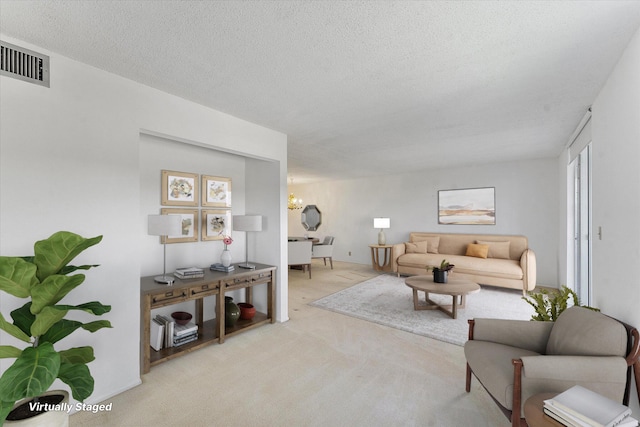 living room with carpet floors, visible vents, a chandelier, and a textured ceiling