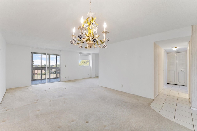 empty room featuring light carpet and a chandelier