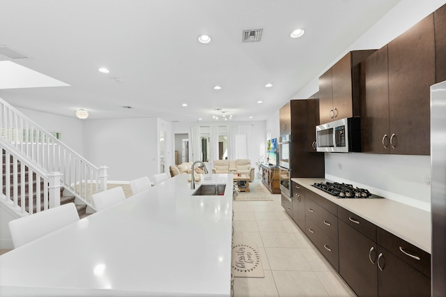 kitchen featuring visible vents, open floor plan, light tile patterned flooring, stainless steel appliances, and a sink