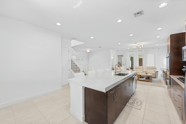 kitchen featuring visible vents, recessed lighting, a sink, dark brown cabinetry, and open floor plan