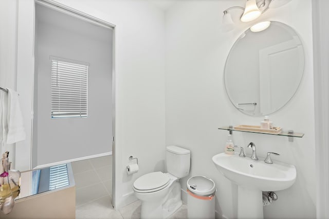 half bath with a sink, toilet, and tile patterned flooring