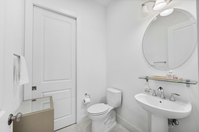 half bath with a sink, baseboards, toilet, and tile patterned floors