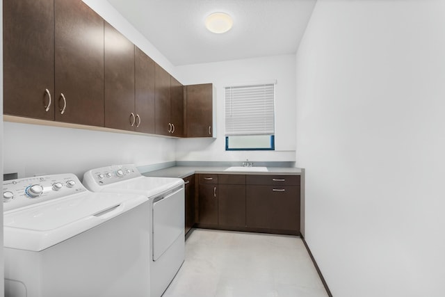 laundry room with washing machine and clothes dryer, cabinet space, light floors, and a sink