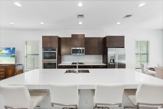 kitchen with light countertops, visible vents, appliances with stainless steel finishes, and a center island with sink