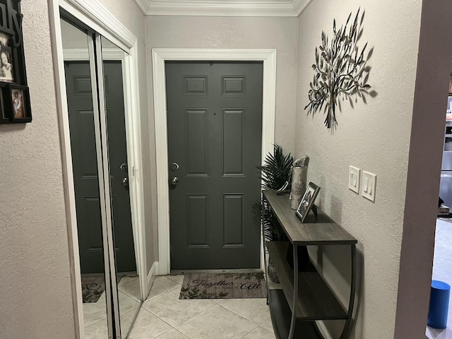 foyer featuring light tile patterned floors, a textured wall, and ornamental molding