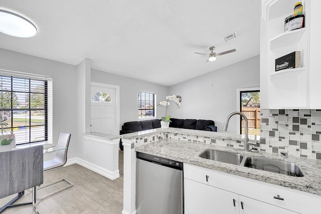 kitchen with tasteful backsplash, visible vents, dishwasher, open floor plan, and a sink