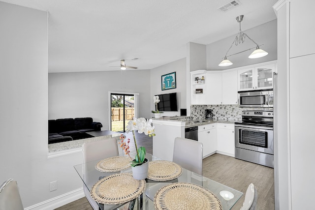 kitchen with appliances with stainless steel finishes, backsplash, visible vents, and light wood-style floors