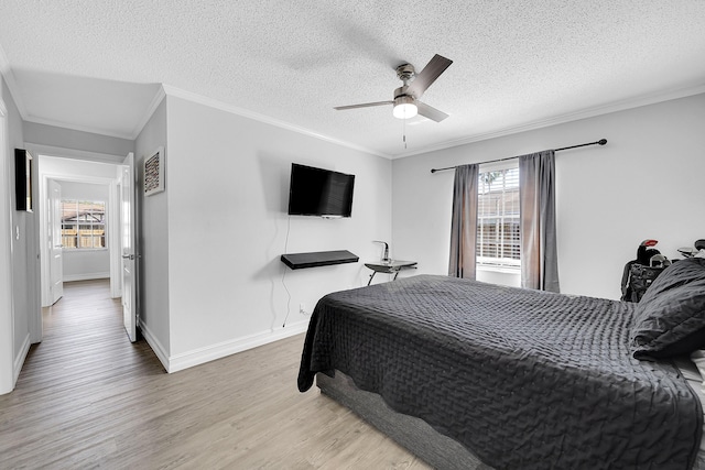 bedroom featuring light wood-type flooring, a textured ceiling, baseboards, and crown molding