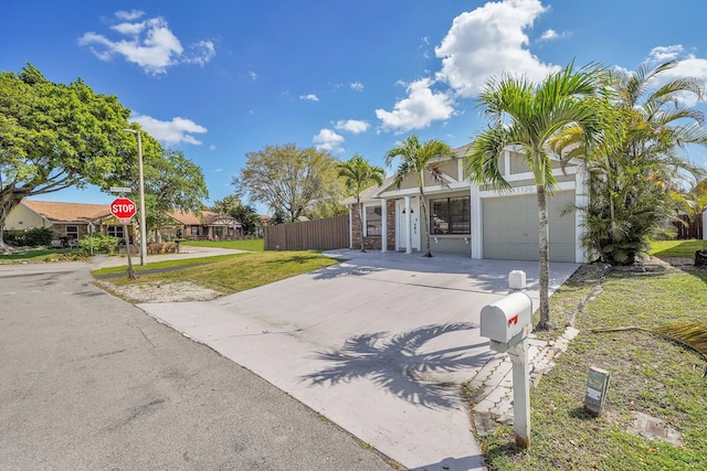 view of front of property featuring a garage, driveway, a front lawn, and fence