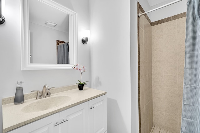 full bathroom featuring vanity, a tile shower, and visible vents