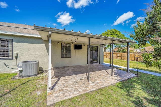 back of property with cooling unit, fence, a yard, stucco siding, and a patio area