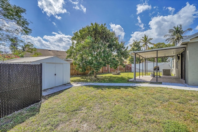 view of yard featuring an outbuilding, a fenced backyard, a patio, and a storage unit