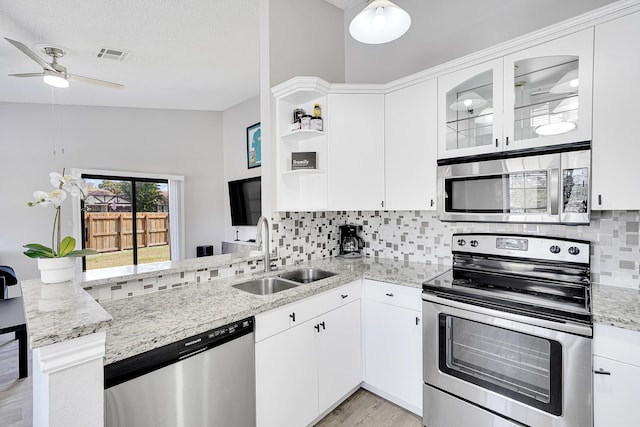 kitchen with stainless steel appliances, a peninsula, a sink, visible vents, and backsplash