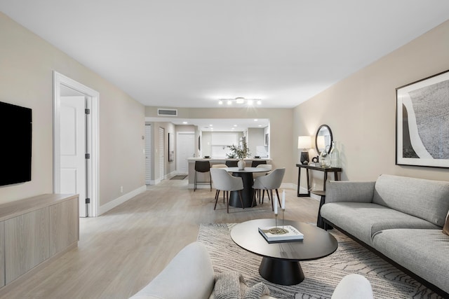 living area featuring light wood-style floors, baseboards, and visible vents