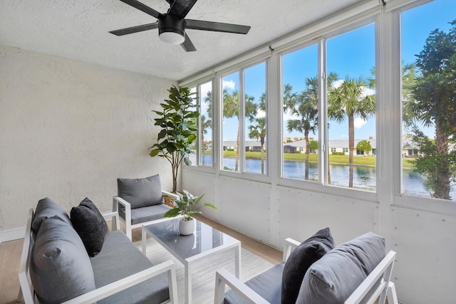 sunroom featuring a water view and ceiling fan