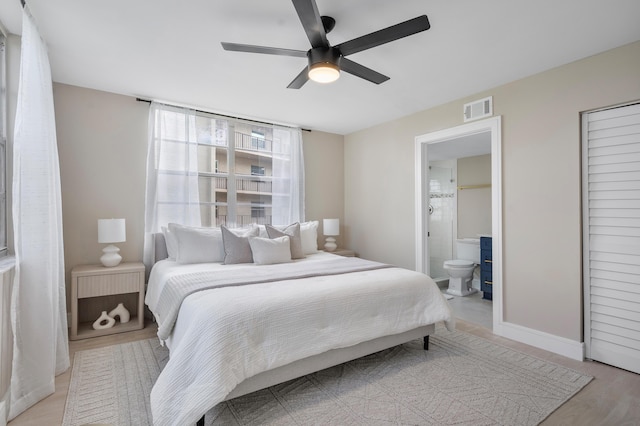 bedroom featuring visible vents, a ceiling fan, ensuite bath, light wood-type flooring, and baseboards