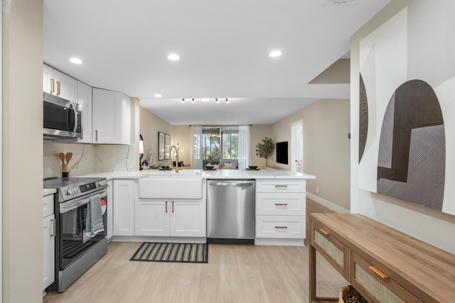 kitchen with stainless steel appliances, tasteful backsplash, light wood-style floors, a sink, and a peninsula