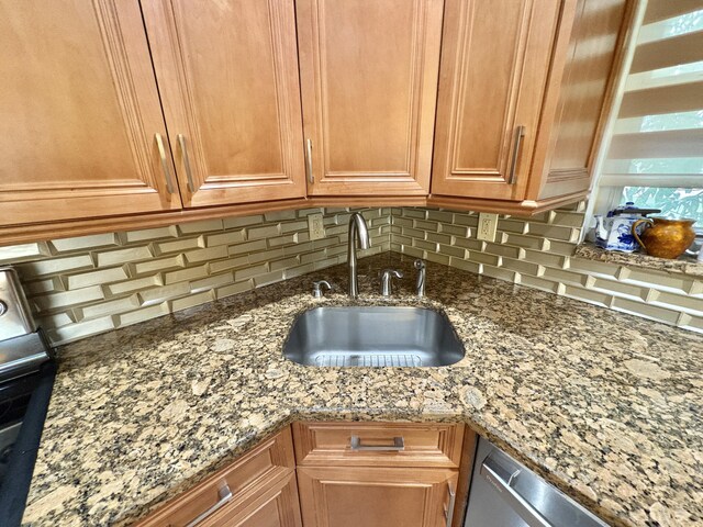 kitchen featuring a sink, backsplash, light stone countertops, dishwasher, and brown cabinetry