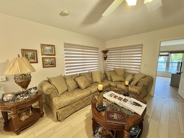 living area with light wood-style floors, a textured ceiling, and a ceiling fan