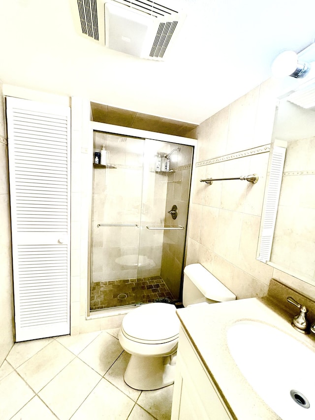 bathroom with a stall shower, visible vents, tile walls, and toilet