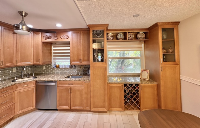 kitchen with dishwasher, a sink, and light stone countertops