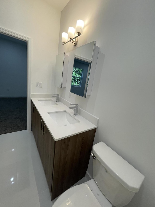 bathroom with a sink, toilet, and double vanity