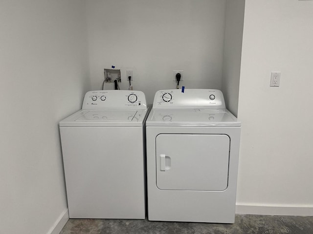 clothes washing area featuring washer and clothes dryer, laundry area, and baseboards