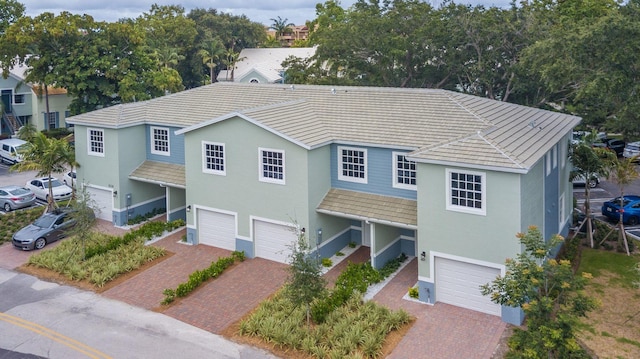 view of front of property with decorative driveway, a garage, and stucco siding