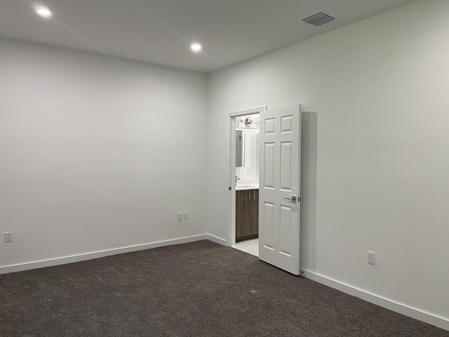 unfurnished room with visible vents, baseboards, recessed lighting, a sink, and dark colored carpet