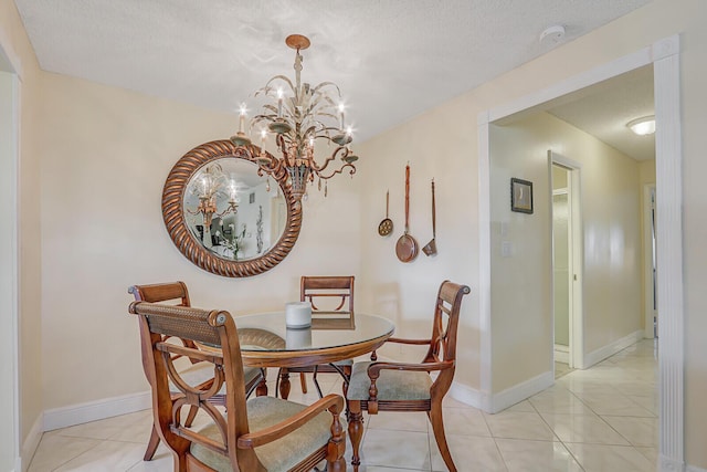 dining area with light tile patterned flooring, a notable chandelier, a textured ceiling, and baseboards