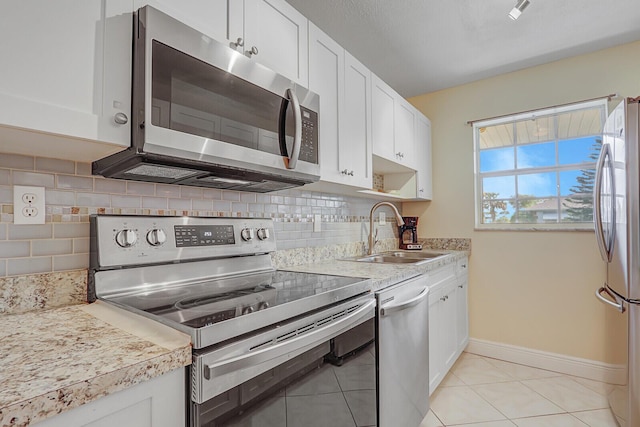 kitchen with appliances with stainless steel finishes, light countertops, white cabinetry, and a sink