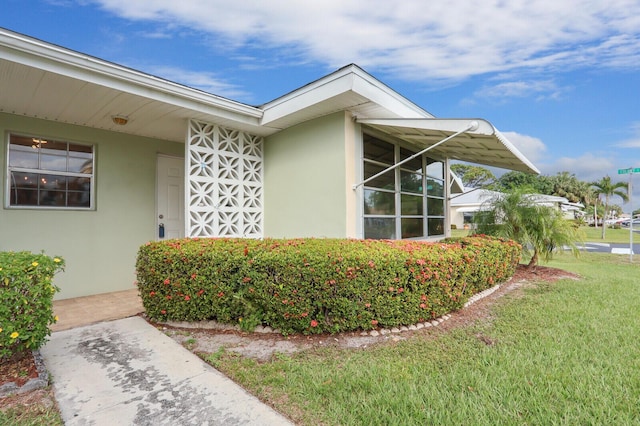 property entrance with a lawn and stucco siding