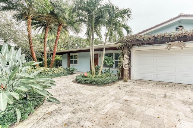 single story home featuring an attached garage, decorative driveway, and stucco siding