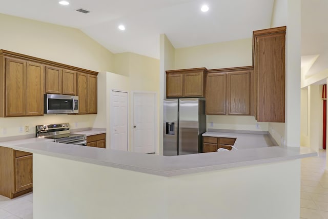 kitchen featuring light tile patterned floors, stainless steel appliances, vaulted ceiling, light countertops, and brown cabinetry