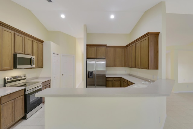 kitchen with light tile patterned floors, light countertops, appliances with stainless steel finishes, vaulted ceiling, and a sink