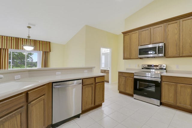 kitchen featuring lofted ceiling, light countertops, appliances with stainless steel finishes, and brown cabinets