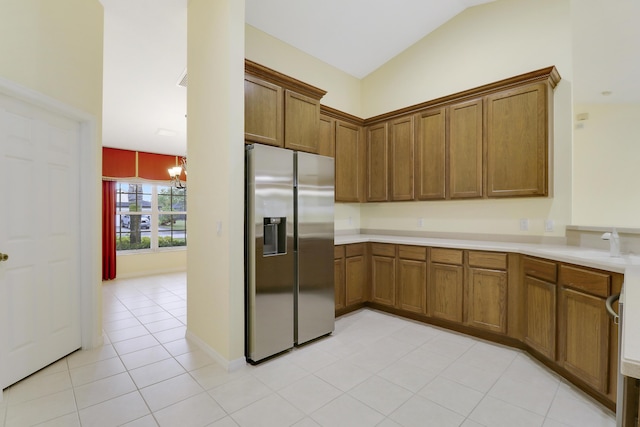 kitchen with brown cabinetry, vaulted ceiling, a sink, and stainless steel fridge with ice dispenser