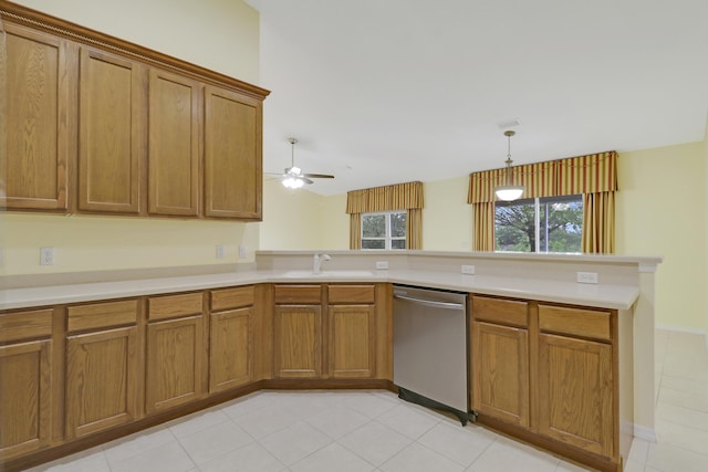 kitchen featuring brown cabinets, light countertops, stainless steel dishwasher, a sink, and a peninsula