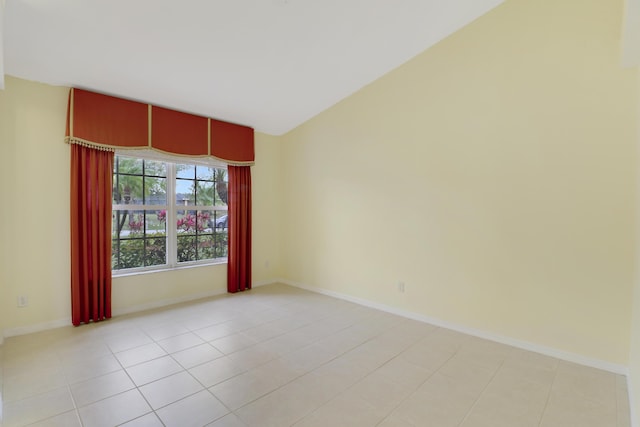 empty room featuring baseboards, vaulted ceiling, and light tile patterned flooring