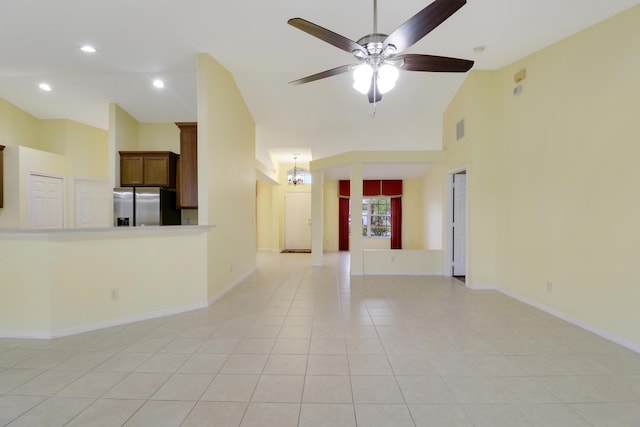 unfurnished living room with light tile patterned floors, high vaulted ceiling, ceiling fan with notable chandelier, visible vents, and baseboards