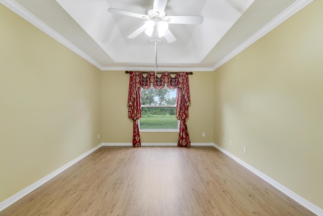 unfurnished room with a tray ceiling, light wood-style floors, ornamental molding, baseboards, and ceiling fan with notable chandelier