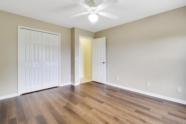 unfurnished bedroom featuring baseboards, visible vents, ceiling fan, wood finished floors, and a closet