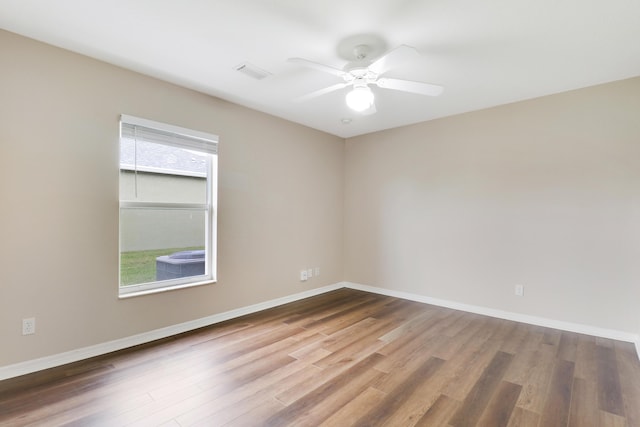 unfurnished room with a ceiling fan, visible vents, baseboards, and wood finished floors