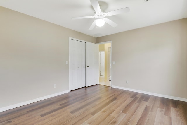 unfurnished bedroom with ceiling fan, a closet, wood finished floors, and baseboards