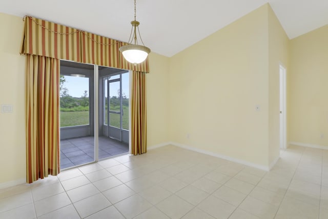 spare room with lofted ceiling, baseboards, and light tile patterned floors